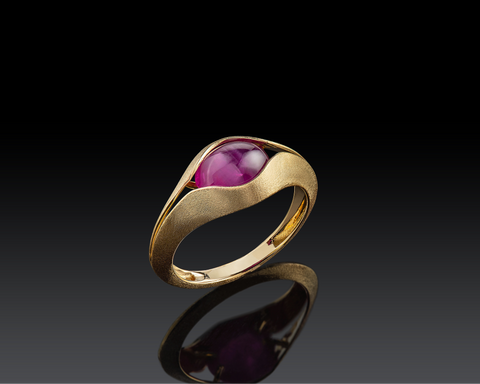 Gold ring with a pink gemstone on a black background