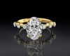 Gold ring with a large diamond and smaller diamonds on a reflective surface