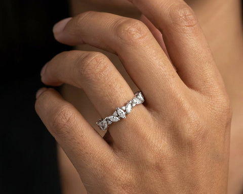 Close-up of a hand wearing a diamond ring with a dark background