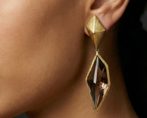 Gold earring with geometric design worn on an ear