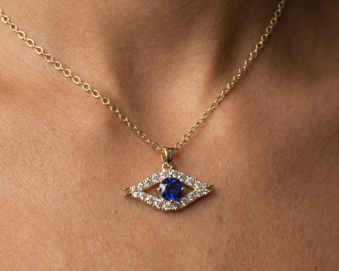 Guardian eye pendant in yellow gold with a blue sapphire, worn at the neckline
