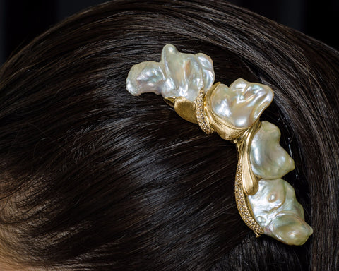 Pearl hair clip on a person's hair against a dark background