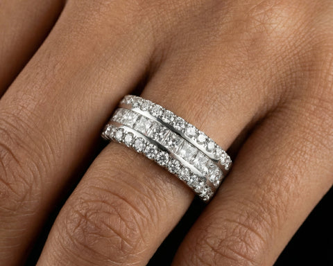 Close-up of a hand wearing a silver ring with multiple diamond bands.