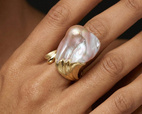 Gold ring with a large pearl on a hand