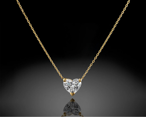 Heart-shaped diamond pendant on a gold chain against a black background