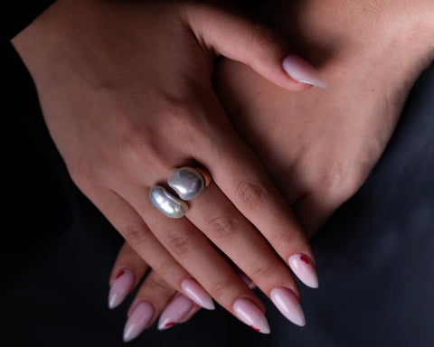 Two Keshi baroque pearl rings in 18K gold, worn on the hand against a dark background