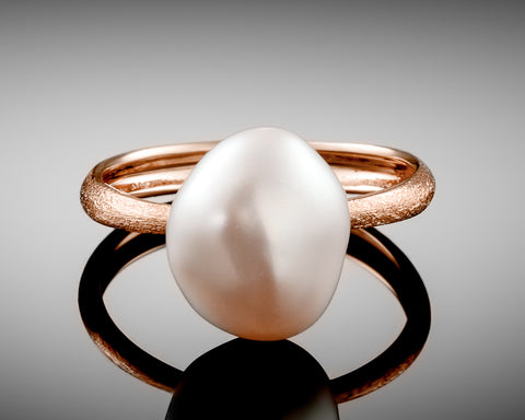 Century ring in rose gold standing upright, showing the pearl from the side
