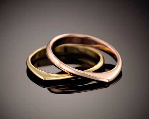Two twisted rings, one gold plated and one rose plated, resting one inside the other