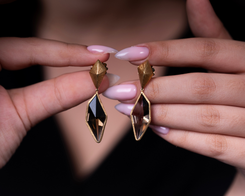 The Edges Of Love earrings held in the hand, showing the open gold frame around the smoky quartz