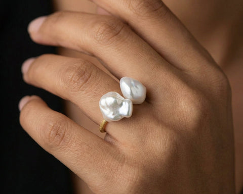 Pearl ring on a hand against a neutral background