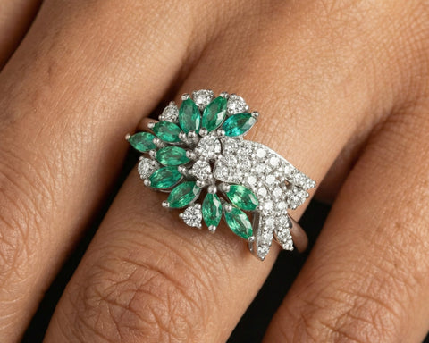 Ring with emeralds and diamonds on a finger