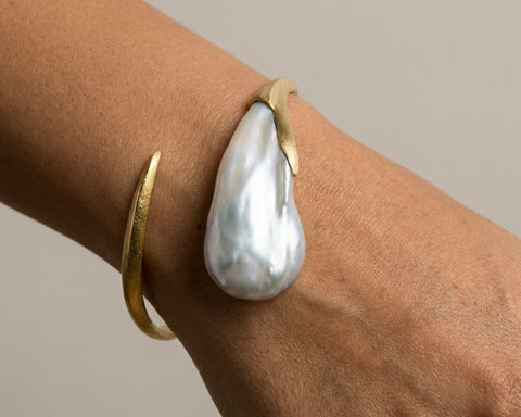 The Flow bangle worn on the wrist, showing the pearl lying along the arm