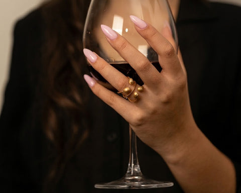 Fugu ring in yellow gold worn on the hand, holding a wine glass