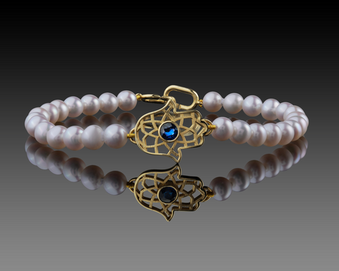 Freshwater pearl bracelet with a gold hamsa holding a blue sapphire