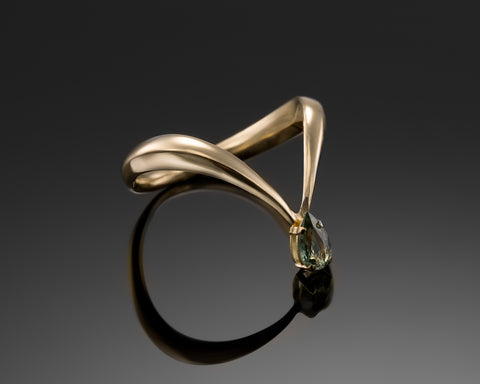 King Of Green ring in yellow gold, a V shaped band with a pear-shaped green sapphire at the tip