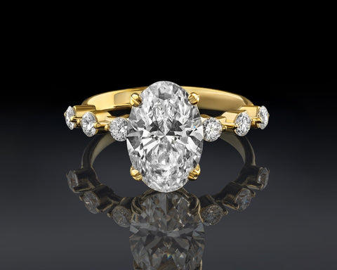 Oval solitaire ring in 14K yellow gold with a 3 carat lab-grown diamond and three side stones on each shoulder