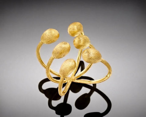 Narwhal ring in yellow gold, six brushed hollow nuggets at the ends of three open bands crossing beneath the finger