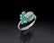 white gold ring with emerald green gemstones on a black background