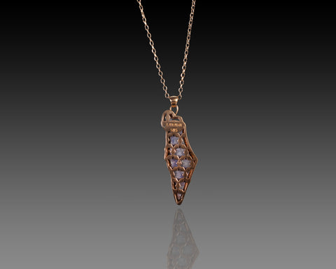 Reverse of the pendant, the gold sawn into a lattice of Stars of David with light passing through the sapphire