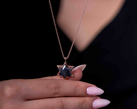   Star of David sapphire pendant held in the hand at the neckline
