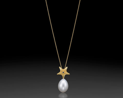 Starfish pendant in 14K yellow gold with granulated texture and a white drop pearl hanging beneath