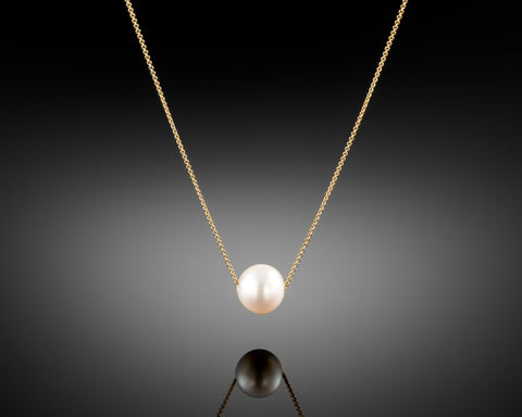 Sun necklace in yellow gold, a single round pearl threaded onto a fine chain