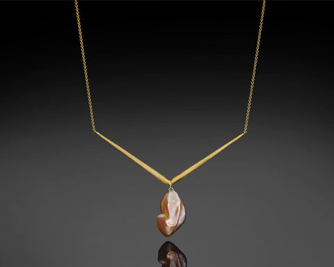 Vega necklace in yellow gold, a chain meeting in a V with a Keshi pearl hanging from the point
