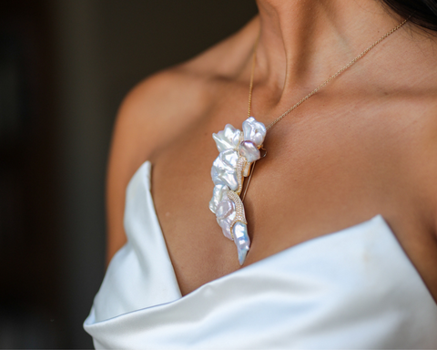 The Wild Horse brooch worn on the shoulder above a white dress