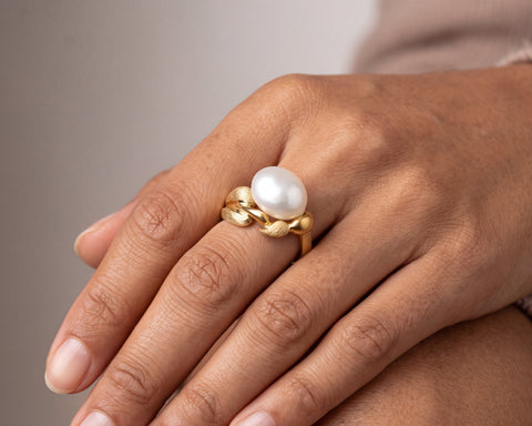 Woman wearing a handmade 18K gold Keshi pearl ring with sculpted leaf setting