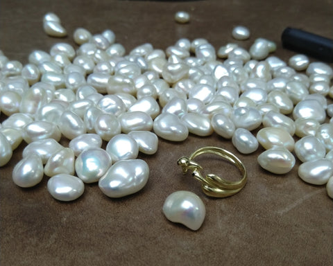 Gold pearl ring on the workbench among loose white Keshi pearls