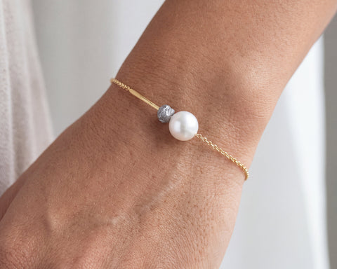 Expedition bracelet worn on the wrist, raw grey diamond beside a freshwater pearl on an 18K yellow gold chain, by LAYANI Fine Jewelry Jerusalem