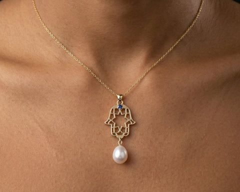 Celestial hamsa pendant with pearl in yellow gold, worn at the neckline
