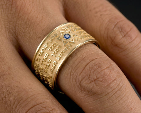 18K yellow gold wide band with the Shema Yisrael raised from the surface and a sapphire set into the metal