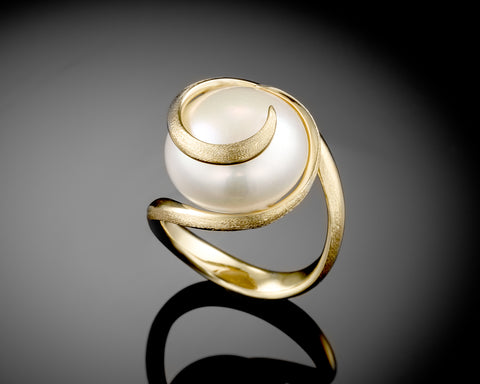 Side view of a gold spiral ring set with a large white bouton pearl
