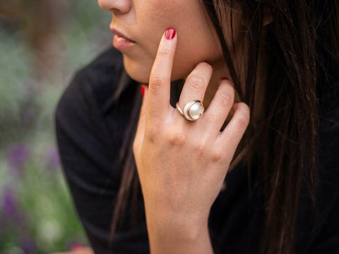 Woman wearing a handmade gold spiral ring with a large white pearl