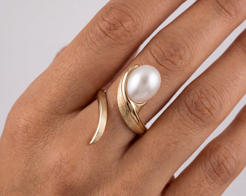 Woman wearing a handmade gold open ring with an oval pearl and brushed finish