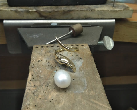 Cast gold open ring on the workbench beside the pearl before setting