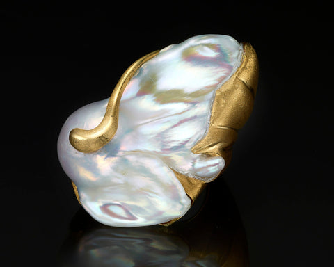 Close view of the Mantle ring, a silvery-white Baroque Keshi pearl wrapped by matte 18K yellow gold with polished veins