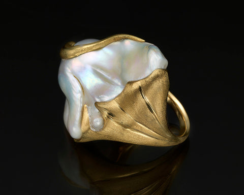 Front view of the Mantle ring on a dark background, the pearl framed by gold on both sides