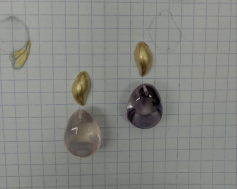 Gold caps and loose rose quartz and amethyst stones beside the original sketch