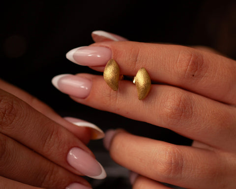 Woman holding the gold studs worn on their own without the stone drops