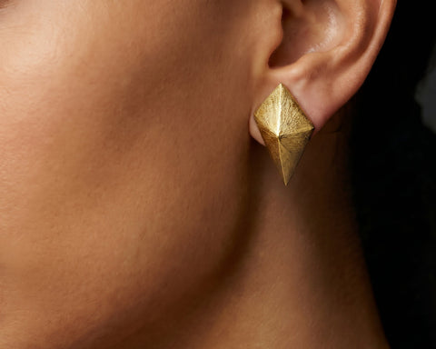 Brushed gold kite shaped stud worn on the lobe