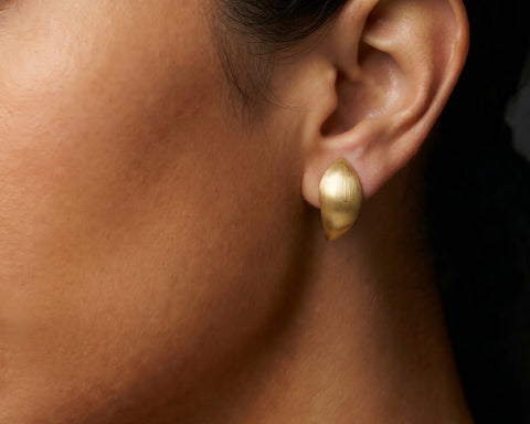 Brushed gold leaf shaped stud worn on the lobe