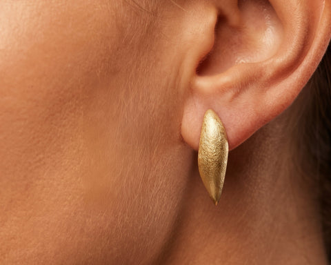 Brushed gold pointed marquise stud worn on the lobe