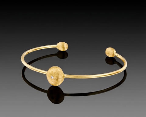 Yellowfin open bangle in yellow gold with a large brushed nugget and diamond at the center and a smaller nugget at each end