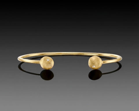 Yellowtail open bangle in yellow gold with a hollow brushed nugget and a diamond at each end