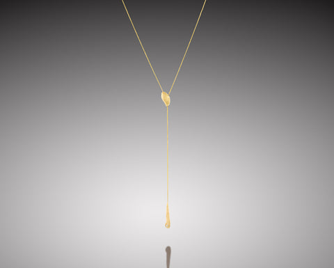Flameback lariat necklace in yellow gold, the chain passing through a brushed nugget and ending in a slim flame-shaped drop with a diamond